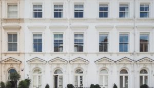 Prince of Wales Terrace building's facade shows rows of symmetrical windows and arched doorways with ornate detailing, rendered in a bright white palette.